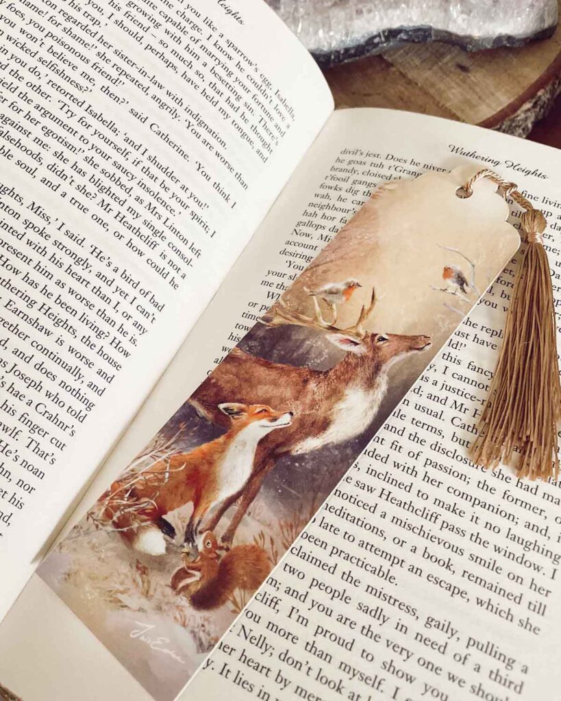 bookmakr with golden tassle featuring a fox, a squirrel and a stag in a shiny winter landscape