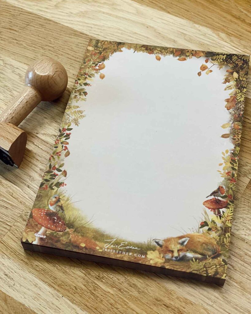 A6 notepad with a woodland border, featuring a sleeping fox, robins, and toadstools among forest leaves.