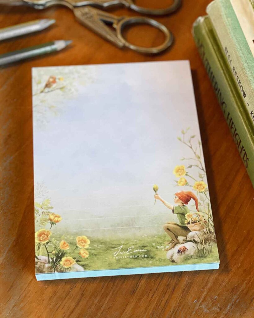 Waldorf-style nature notepad with childlike gnome illustration, robin on a branch, and blooming meadow flowers in warm countryside tones.